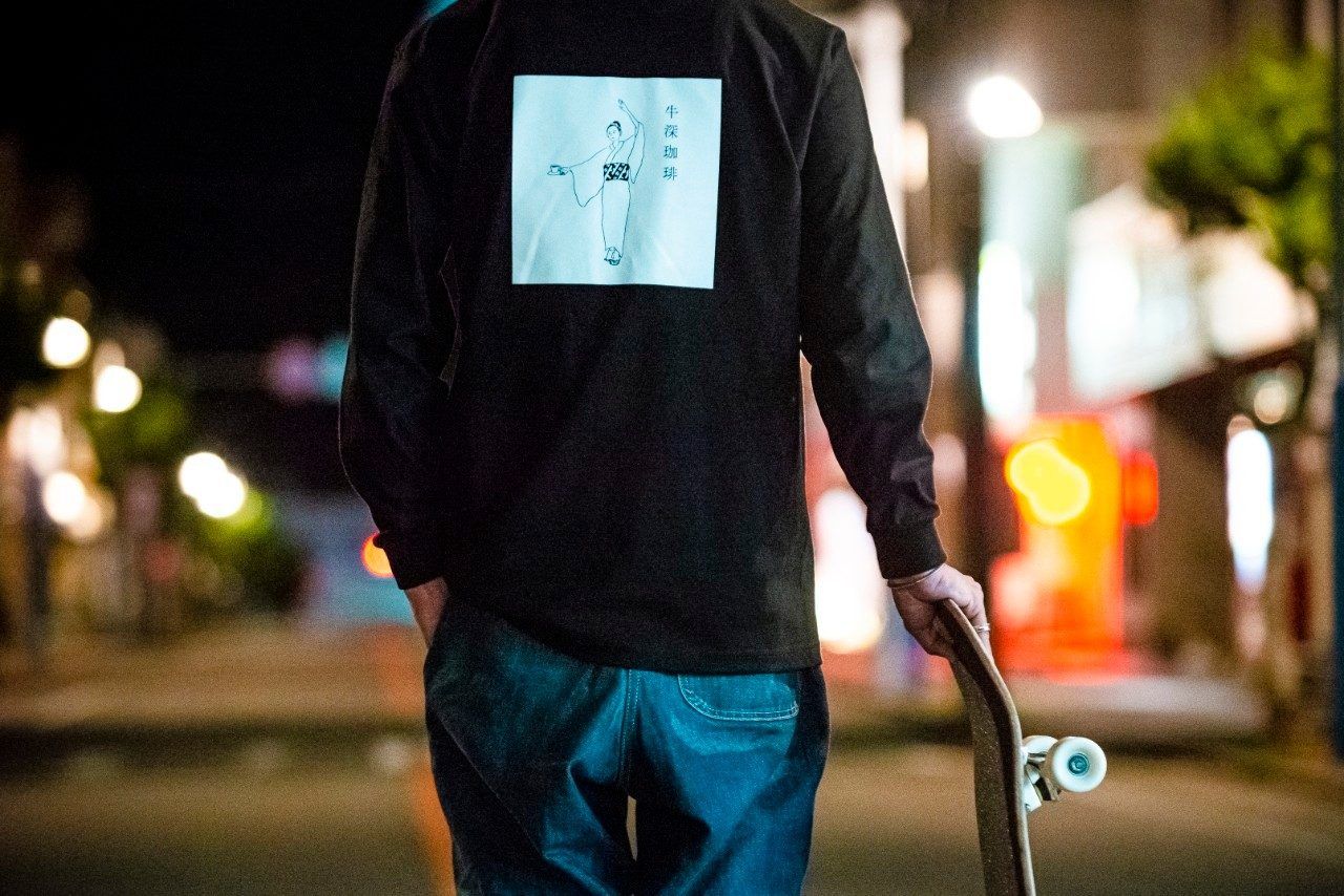 夜の街でスケートボードを持つ後ろ姿