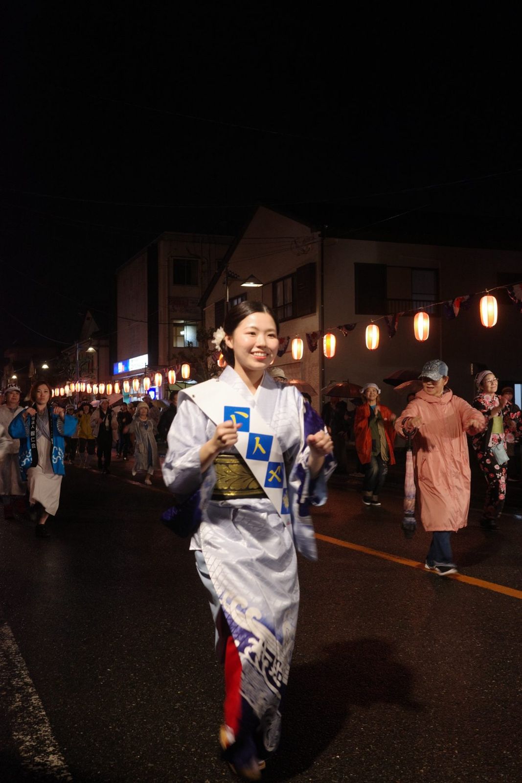 提灯の灯る夜の通りを、笑顔で踊り歩く人たち