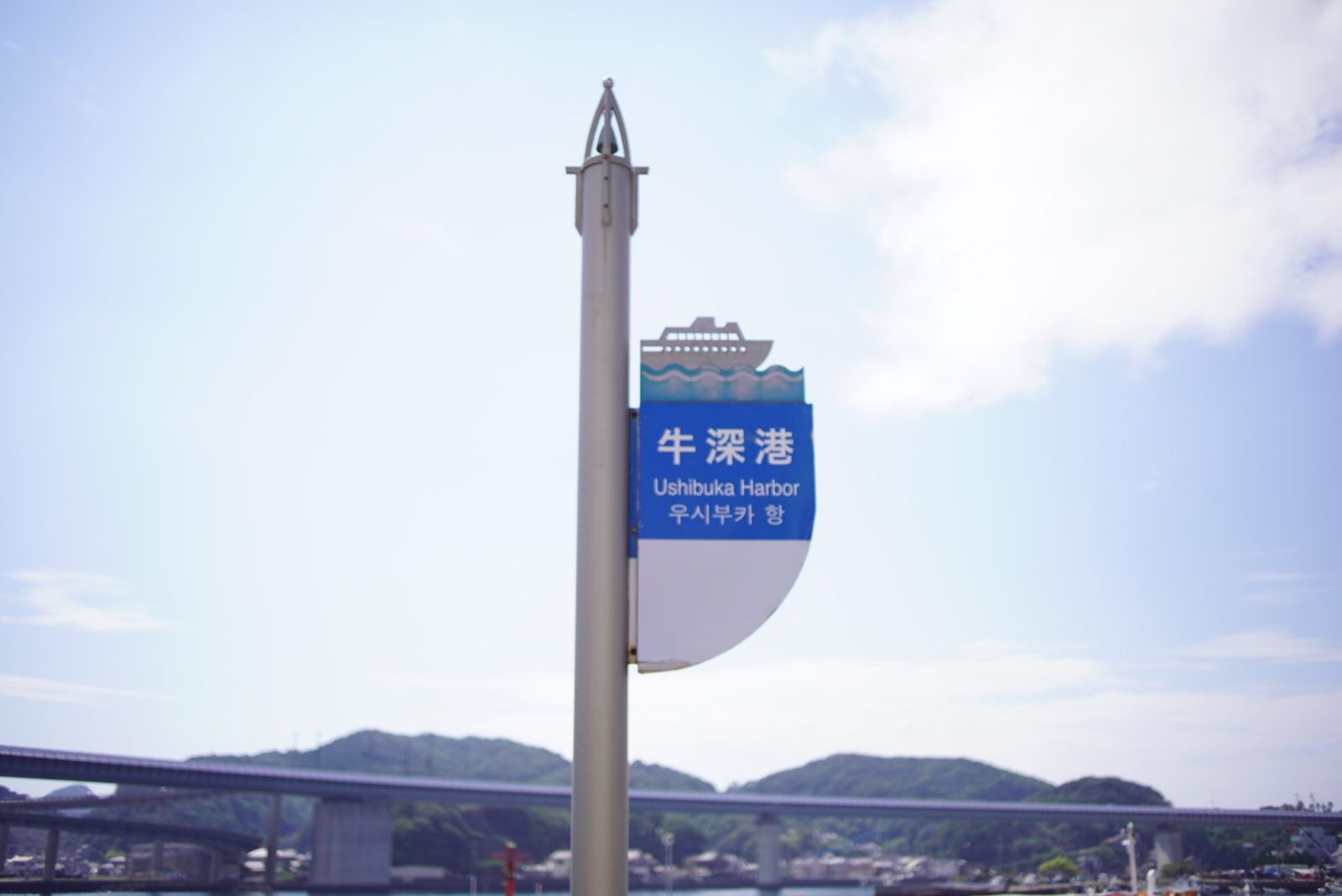 「牛深港」の案内標識と奥にかかる橋